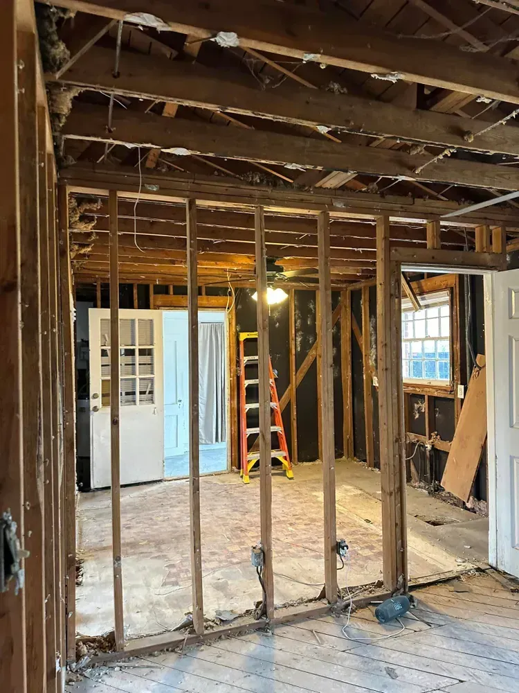 The inside of a house under construction with a ladder in the middle of the room.