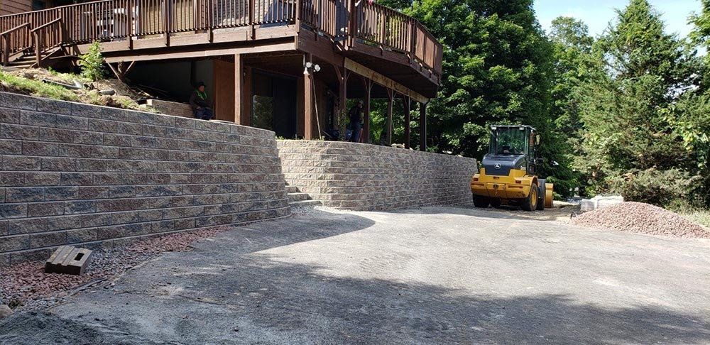 Machine Beside Retaining Wall — Pine Bush, NY — Creative Touch Landscaping & Home Improvement Inc.