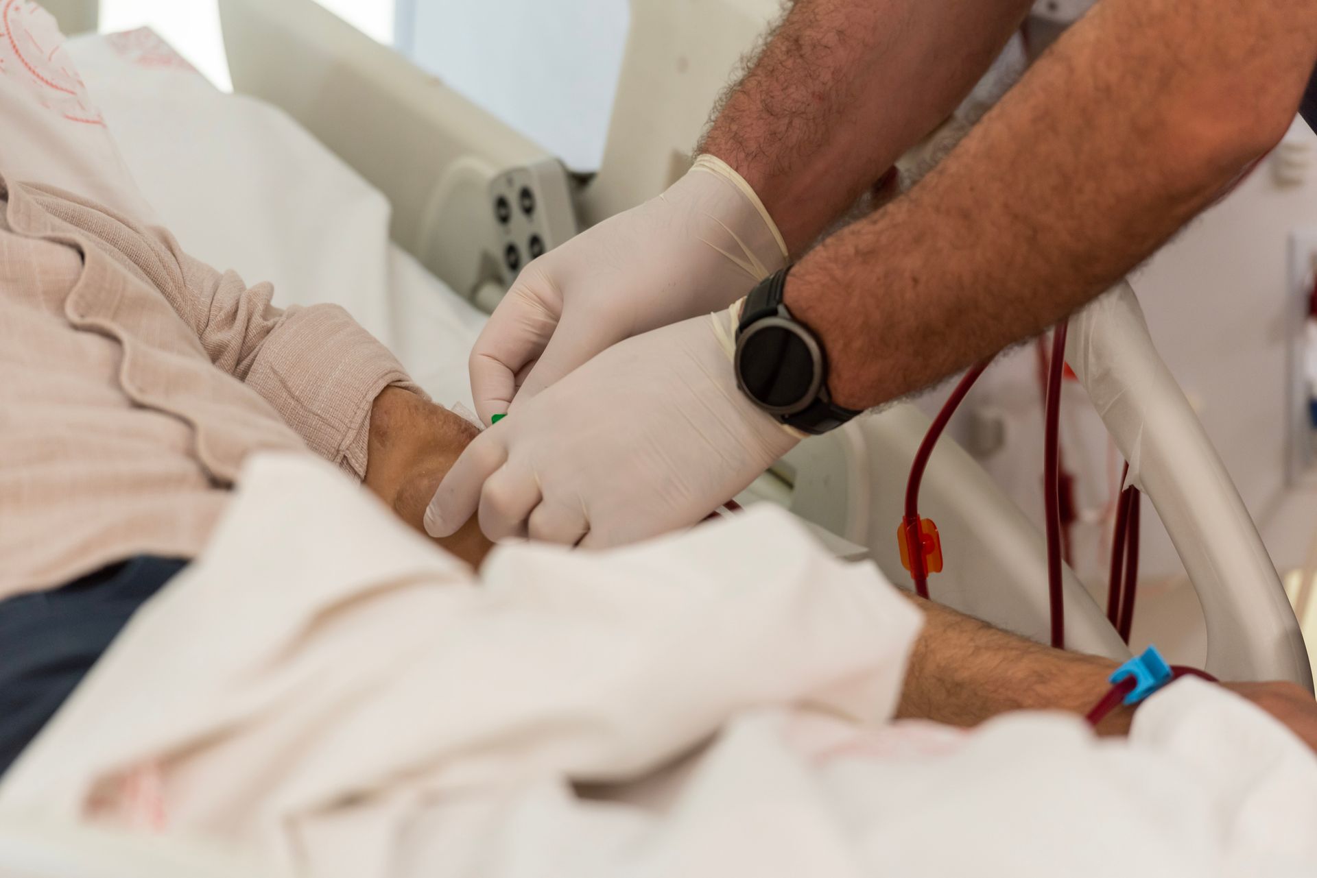 Healthcare Worker in Gloves Adjusting a Medical Line on A Patient's Arm — Highland, UT — Renal Associates of Montgomery PC Healthcare Worker in Gloves Adjusting a Medical Line on A Patient's Arm — Highland, UT — Renal Associates of Montgomery PC