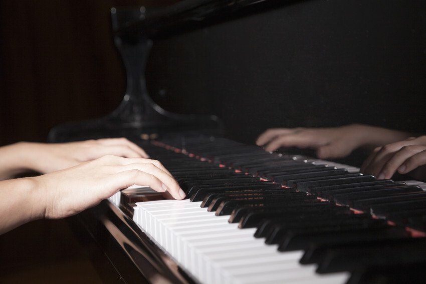 Person is playing a piano in a dark room.
