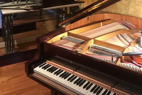 A piano is sitting on a wooden floor in a room.