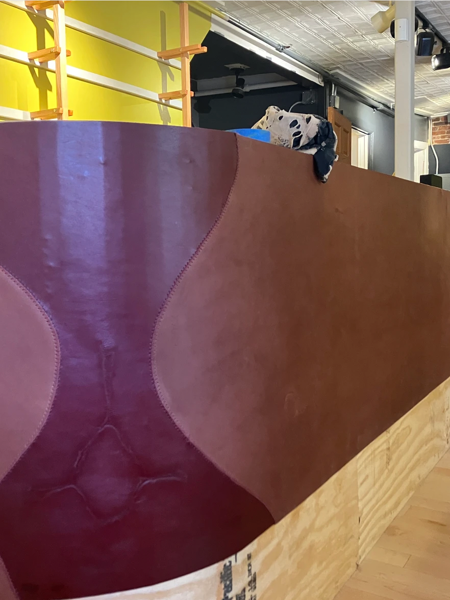 Person painting a curved wall in shades of red and brown.