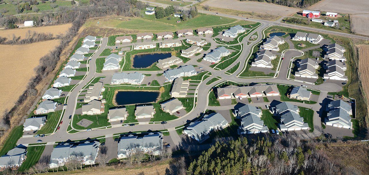 An aerial view of a residential area with lots of houses and a pond.