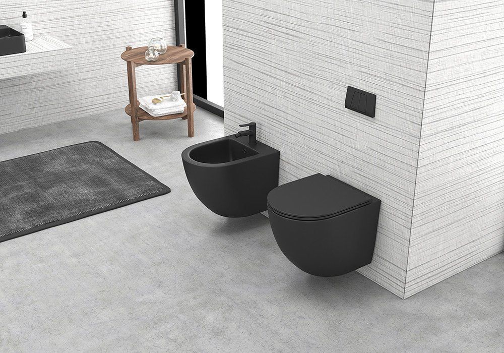 Bagno moderno con bidet e WC sospesi in nero opaco, incassati in una parete rivestita di piastrelle bianche con finitura texturizzata su pavimento grigio.