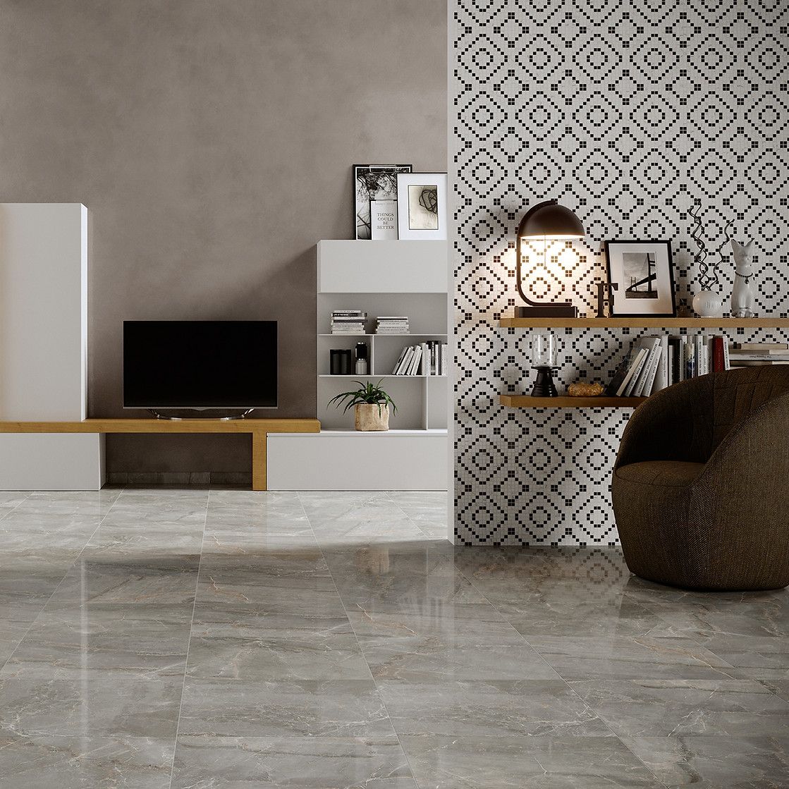Soggiorno con pavimento piastrellato grigio, mobile TV minimalista con televisore, parete decorativa con motivo, mensole e poltrona.