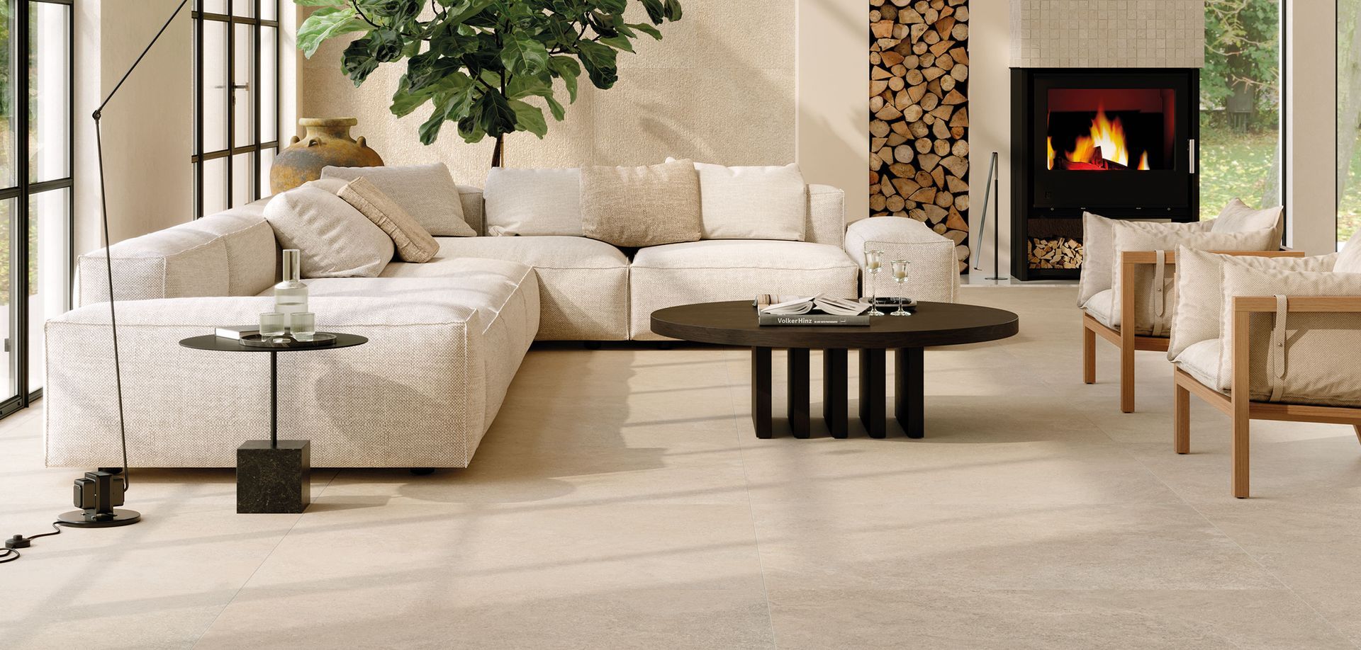 Un accogliente soggiorno con un grande divano angolare beige, un tavolino da caffè in legno scuro, due poltrone in legno e un camino.