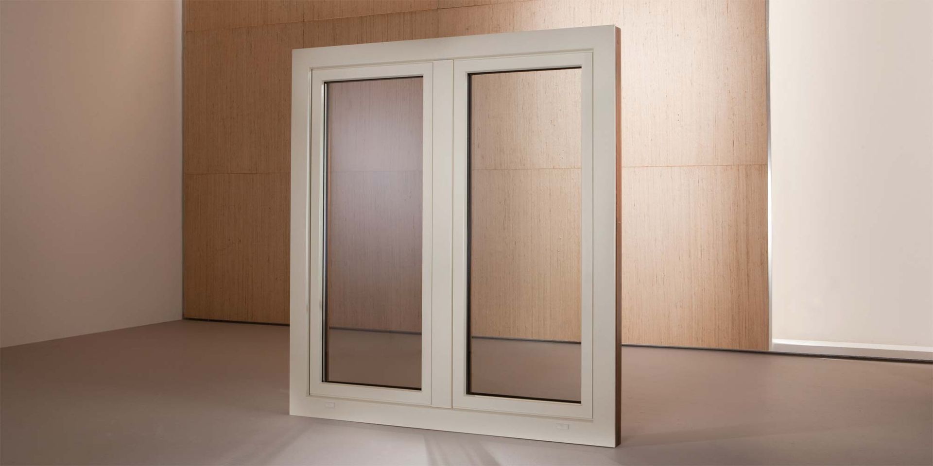 In un ambiente interno, una finestra a doppio vetro con cornice bianca si erge verticalmente contro una semplice parete di legno.