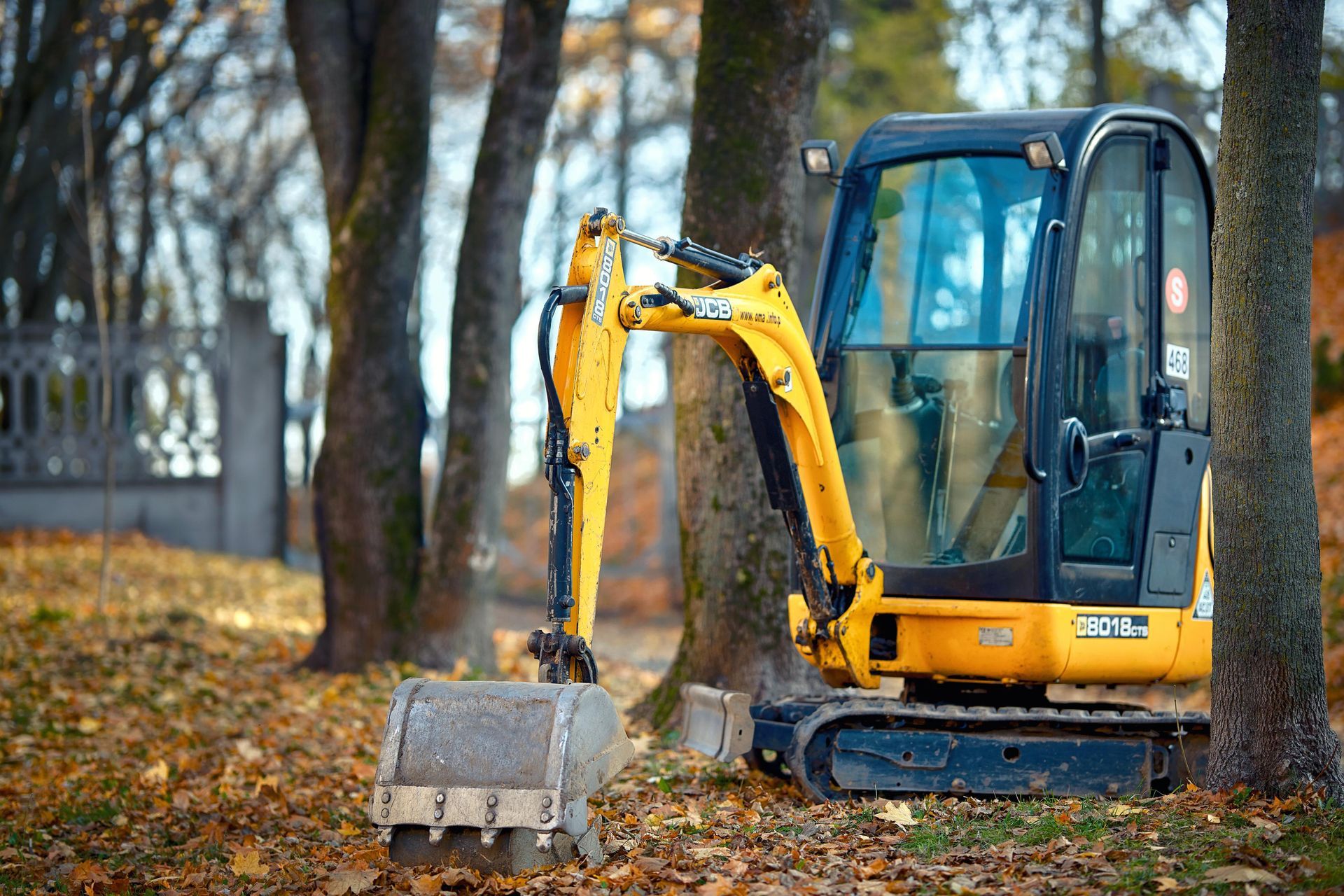 a small yellow excavator is sitting in the middle of a forest .