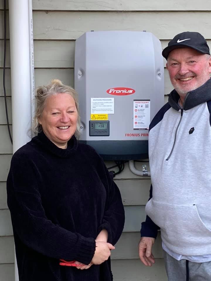 Senior Couple Stand in Front of A Fronius Inverter — Off Grid Solar in Lake Gardens VIC
