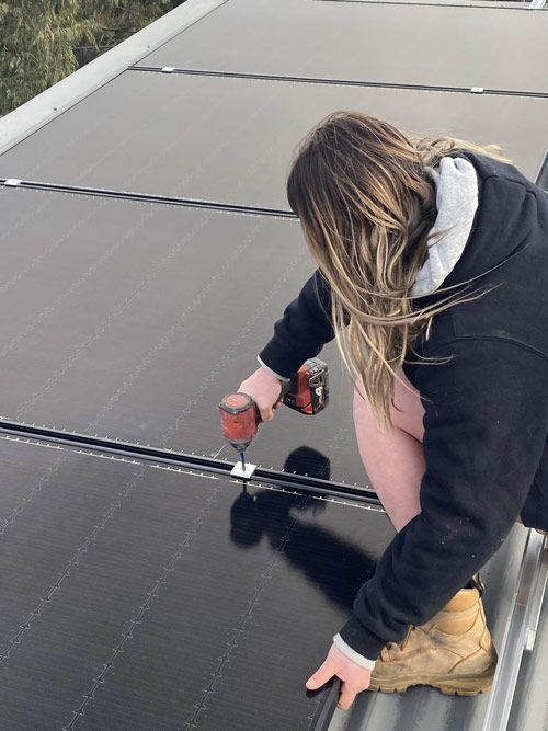 Woman Using Portable Drill Installing Solar Panel — Electrical Services in Lake Gardens VIC