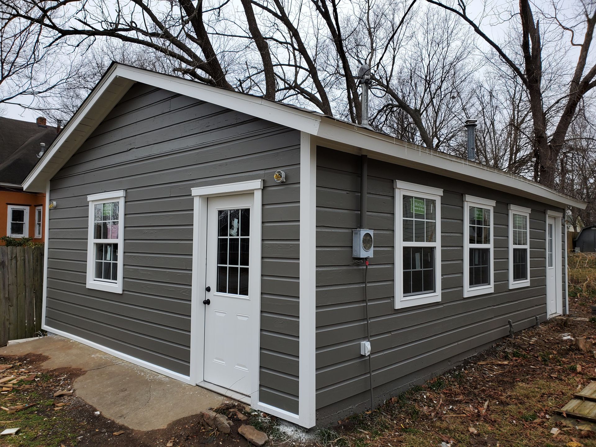 A small gray house with white trim and windows.