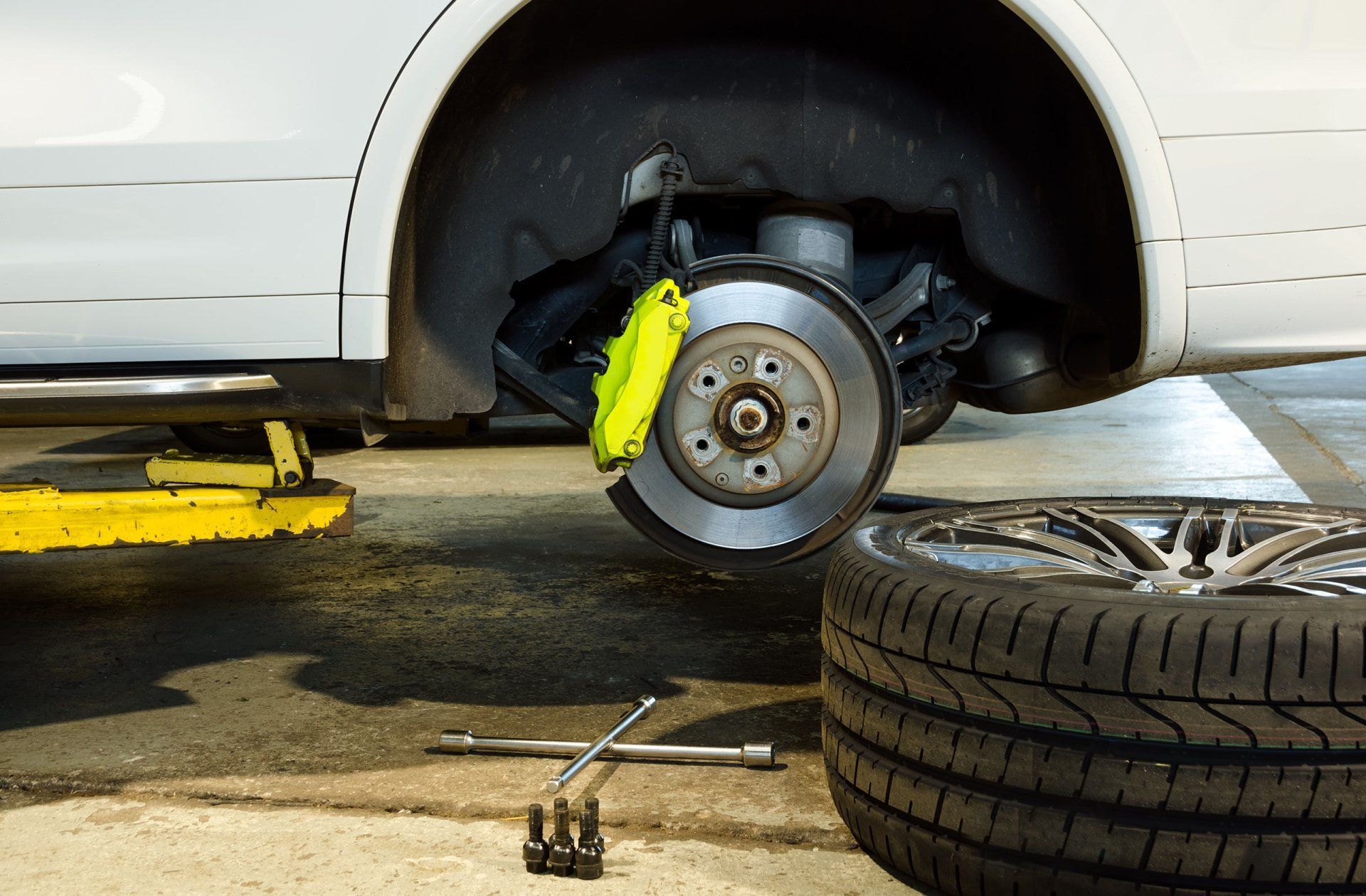 A car is being repaired in a garage with a tire being changed.