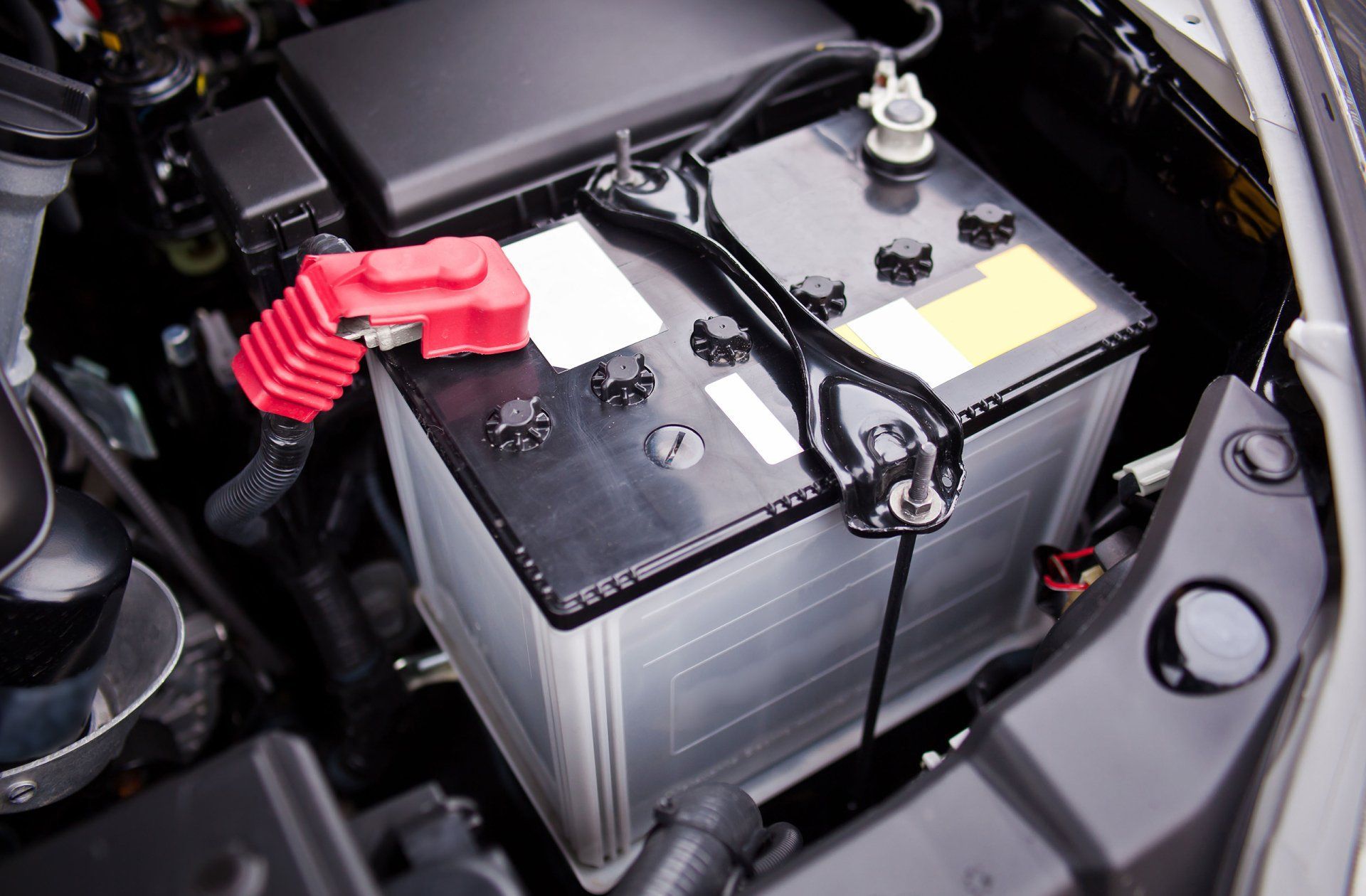 A car battery is sitting under the hood of a car.