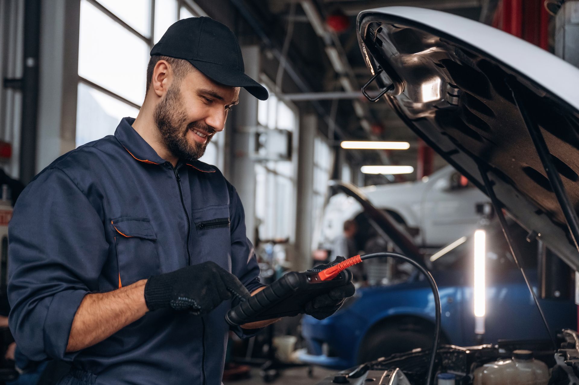 A man is working on a car in a garage with the hood open.