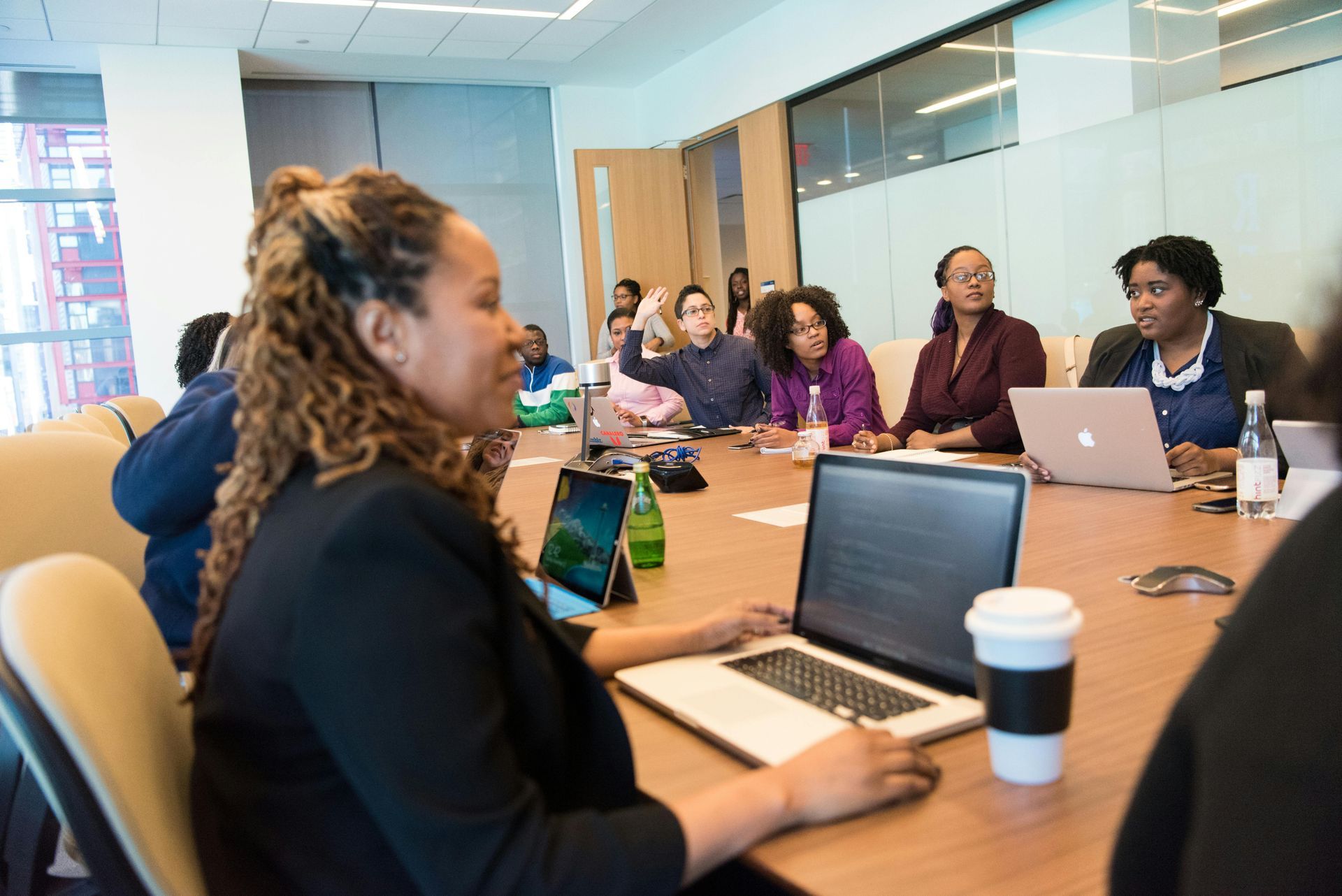A group of people are sitting around a table with laptops.