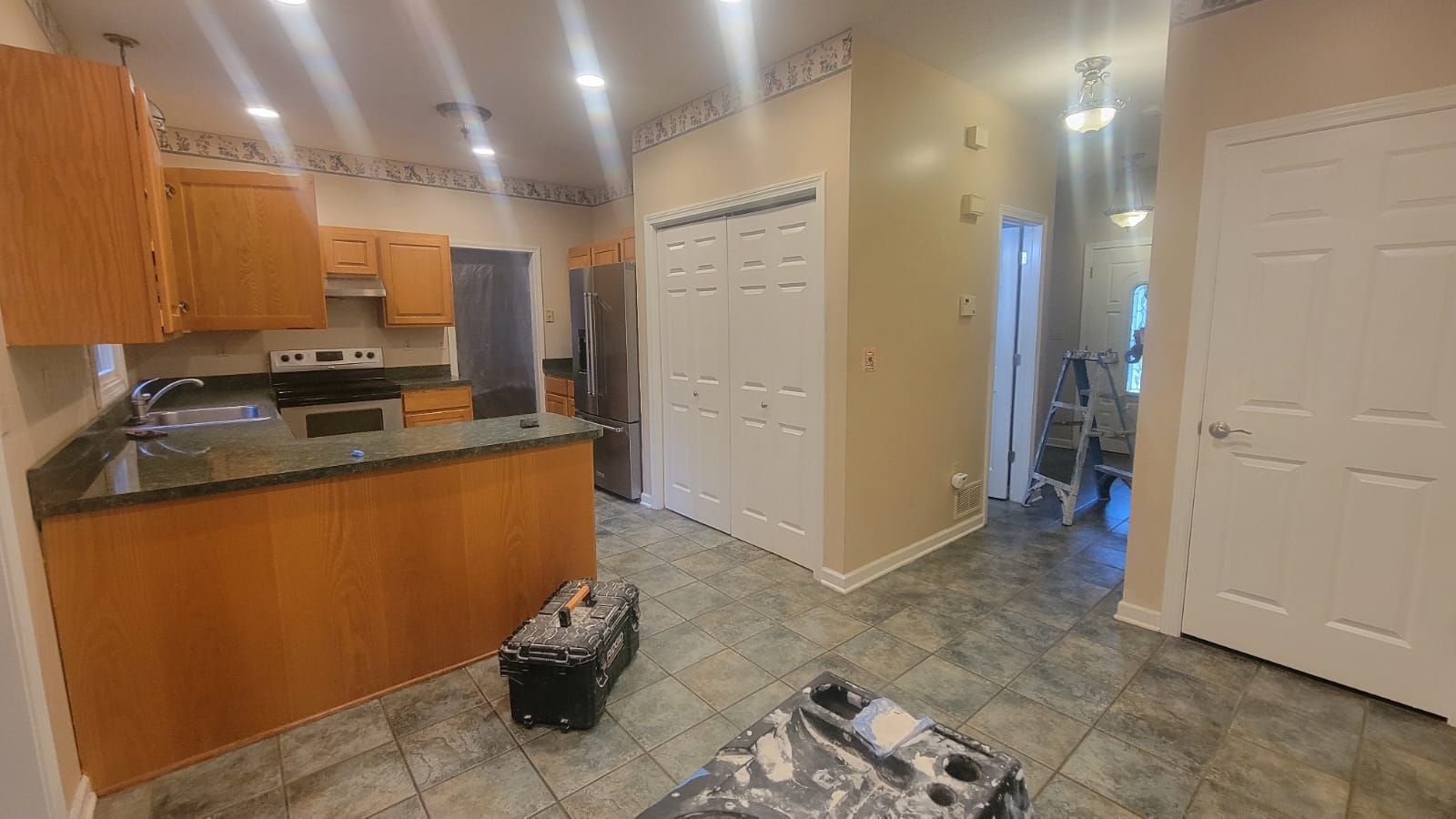 Kitchen with wood cabinets, granite countertops, stainless steel refrigerator, and tiled floor.