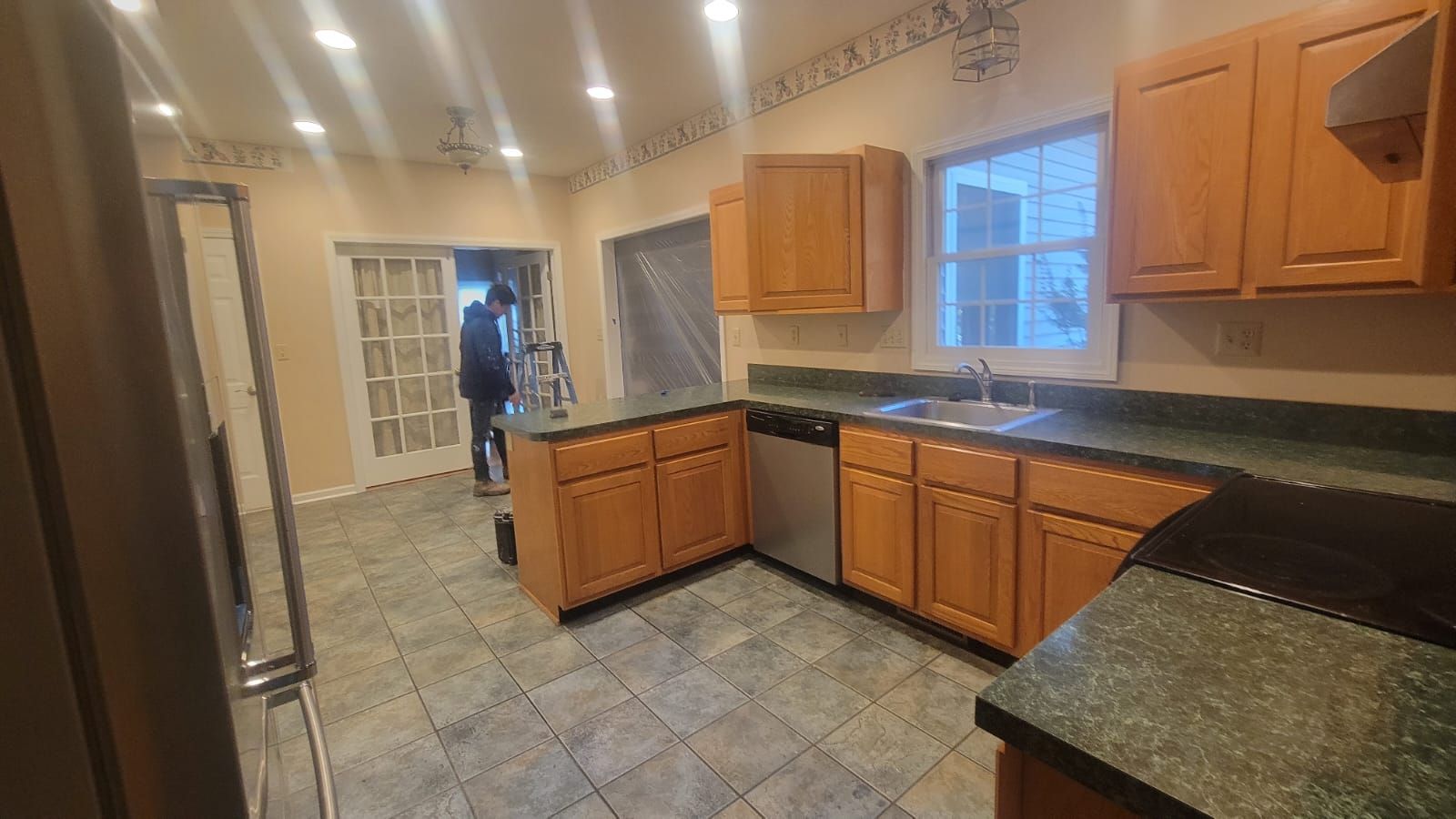 Kitchen with wooden cabinets, green countertops, and a person near a doorway.