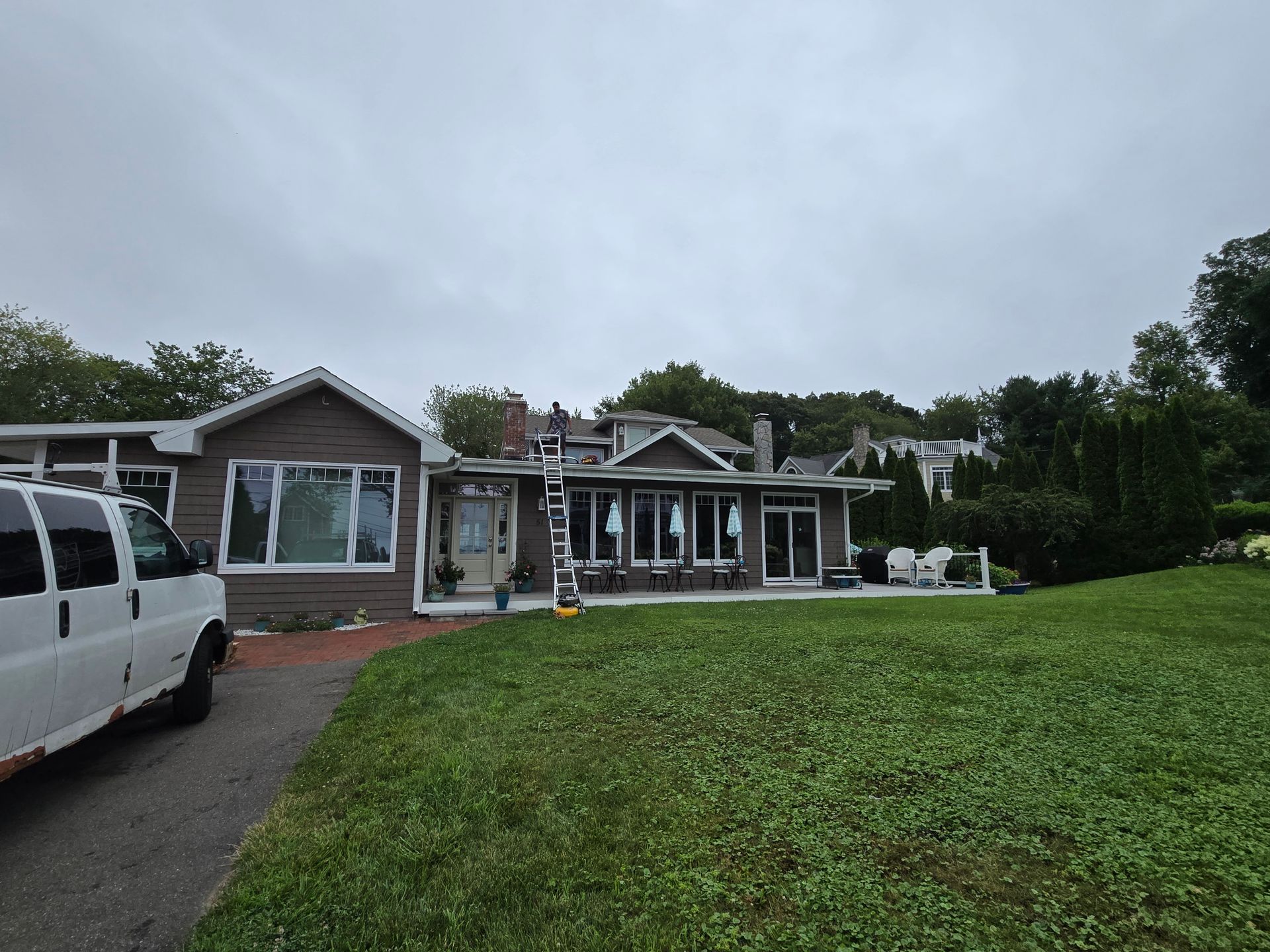 House with gray siding, white trim, and lawn on an overcast day; a white van parked in the driveway.