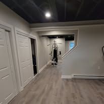 A gym with a weight machine and hardwood floors. Two white doors on the left.