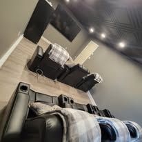 Black leather recliners in a home theater, with a plaid blanket and wood floors.