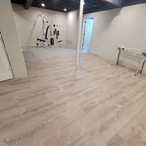 Light wood-look flooring in a finished basement with exercise equipment; black ceiling.