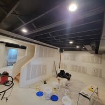 Renovation in progress; room with unfinished walls, exposed ceiling beams, and tools scattered.