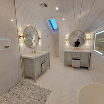 Modern bathroom with two vanities, natural light from a skylight, and wood-planked ceiling.