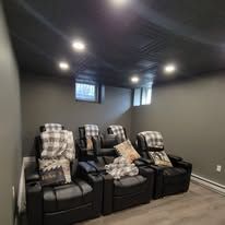 Black leather recliners in a dark room.  Window, textured ceiling, and gray walls.