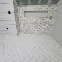 Bathroom with white herringbone floor and hexagon tile wall, unfinished ceiling, and a window.