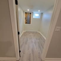 View into an empty room with a window and light-colored flooring. Seen from a doorway.