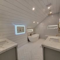 Bathroom with a white tub, white walls, and a white vanity with light fixtures.