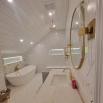 Modern bathroom with a white tub, mirror, and sink. White walls and ceiling.