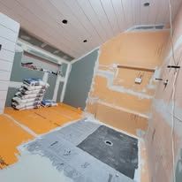 Bathroom under construction with orange flooring, drywall, and exposed plumbing.