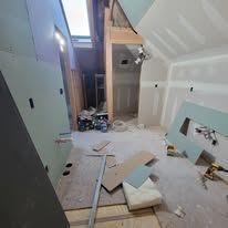 Interior view of a room under construction, unfinished walls, exposed wood, and drywall.