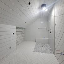 Empty, white-paneled bathroom with tiled floor and recessed lighting.