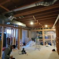 Basement with exposed wooden beams, ductwork, and a child.