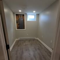 Empty room with a small window, gray walls, and wood-look flooring.