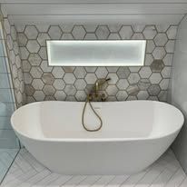 Modern bathroom with a white oval bathtub and hexagon tile backsplash.