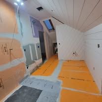 Room under construction with orange flooring, white walls, and an angled ceiling.
