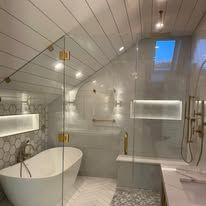 Modern bathroom with a bathtub, glass shower, and a skylight.