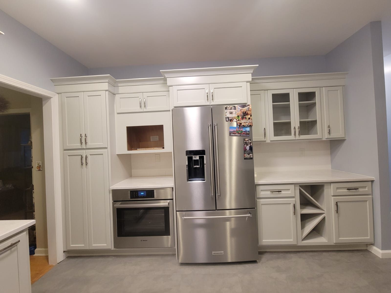 A newly renovated kitchen featuring light grey cabinets, stainless steel appliances, and grey flooring.