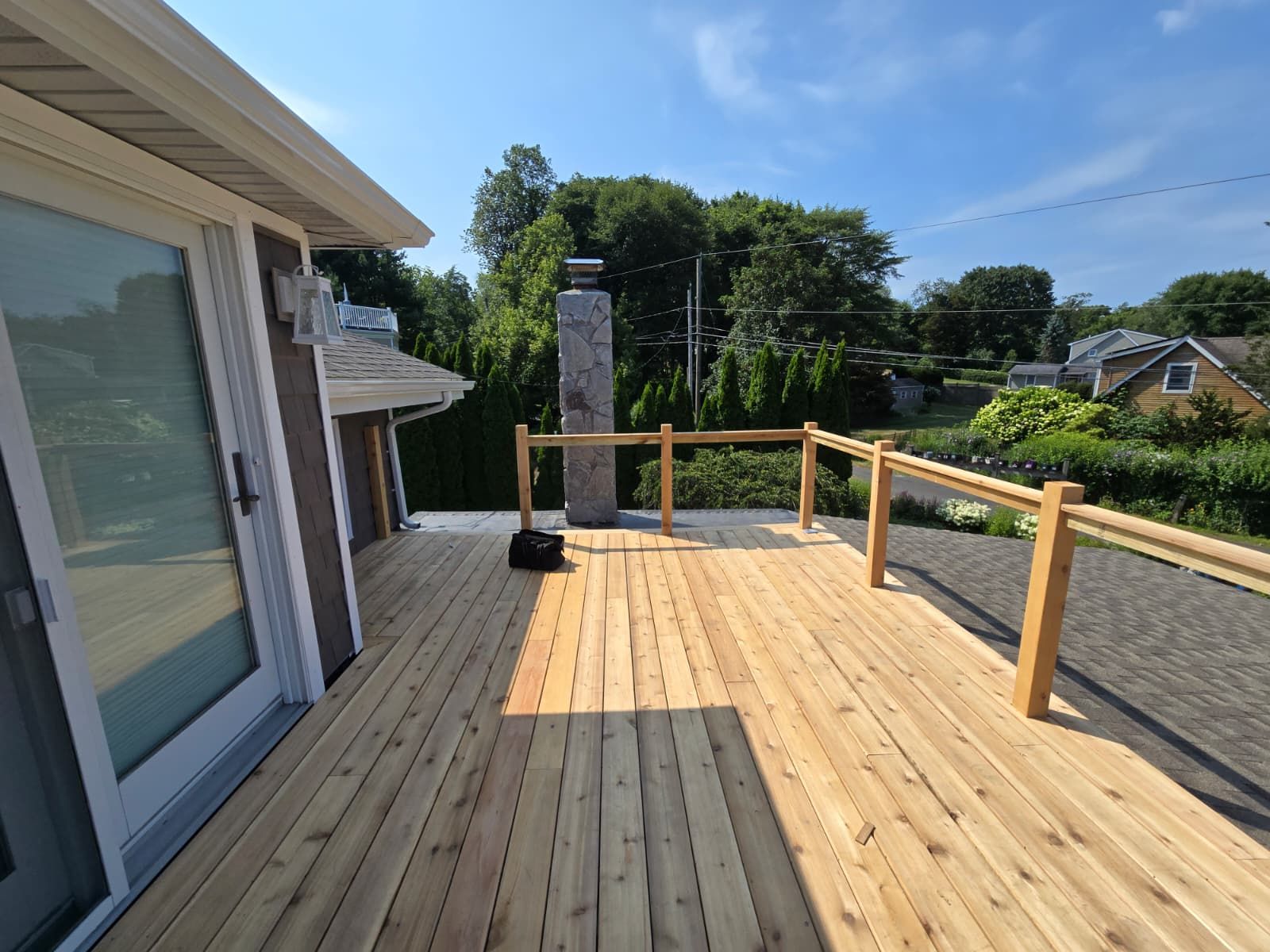 Wooden deck with railing and chimney on a sunny day.