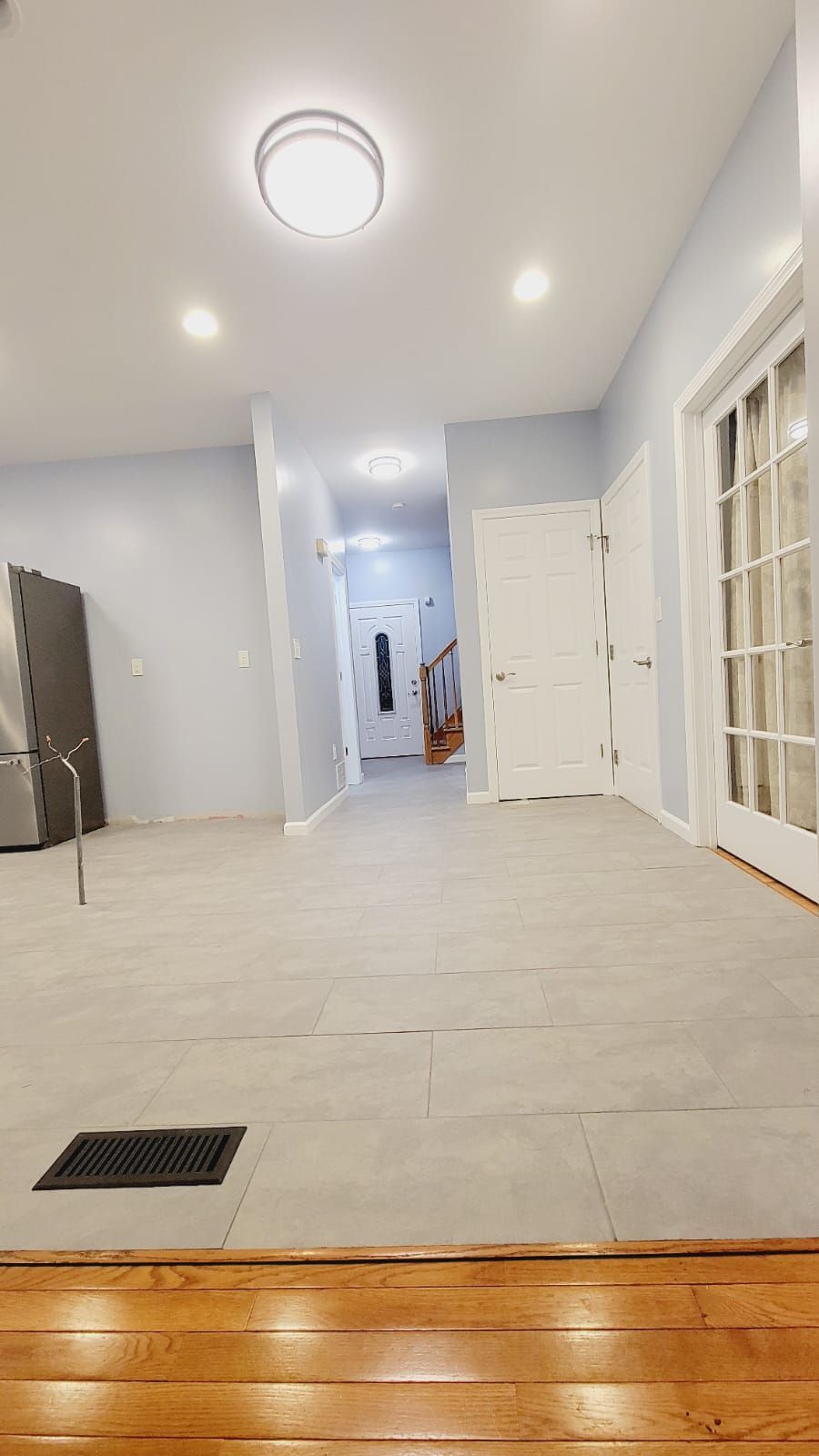 Living room with light gray walls, tiled floor, and wooden trim.