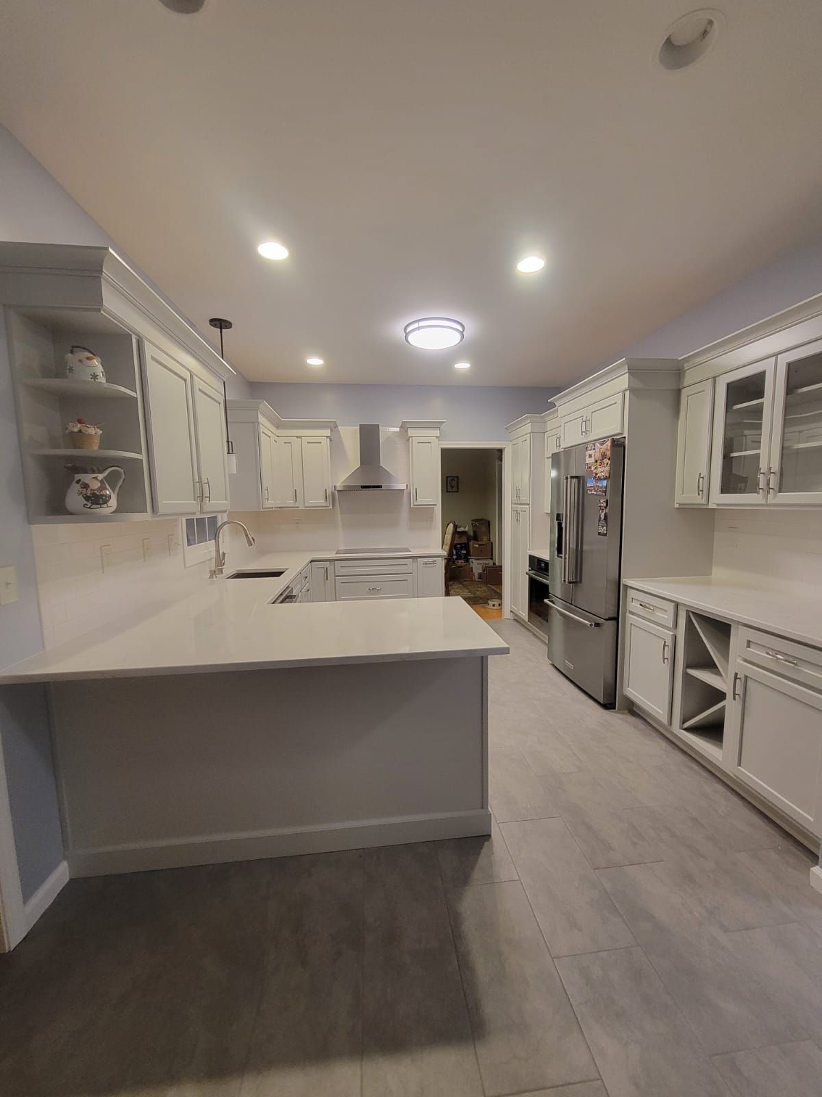 Modern white kitchen with countertops, cabinets, stainless steel appliances, and recessed lighting.