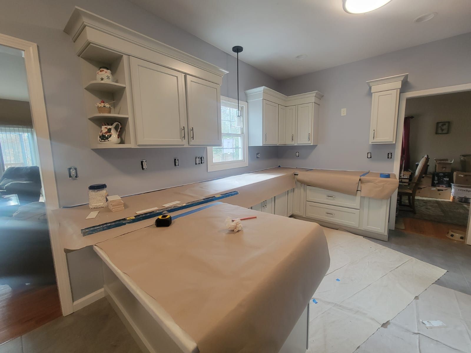 Kitchen under renovation with light gray cabinets and countertops covered in brown paper.