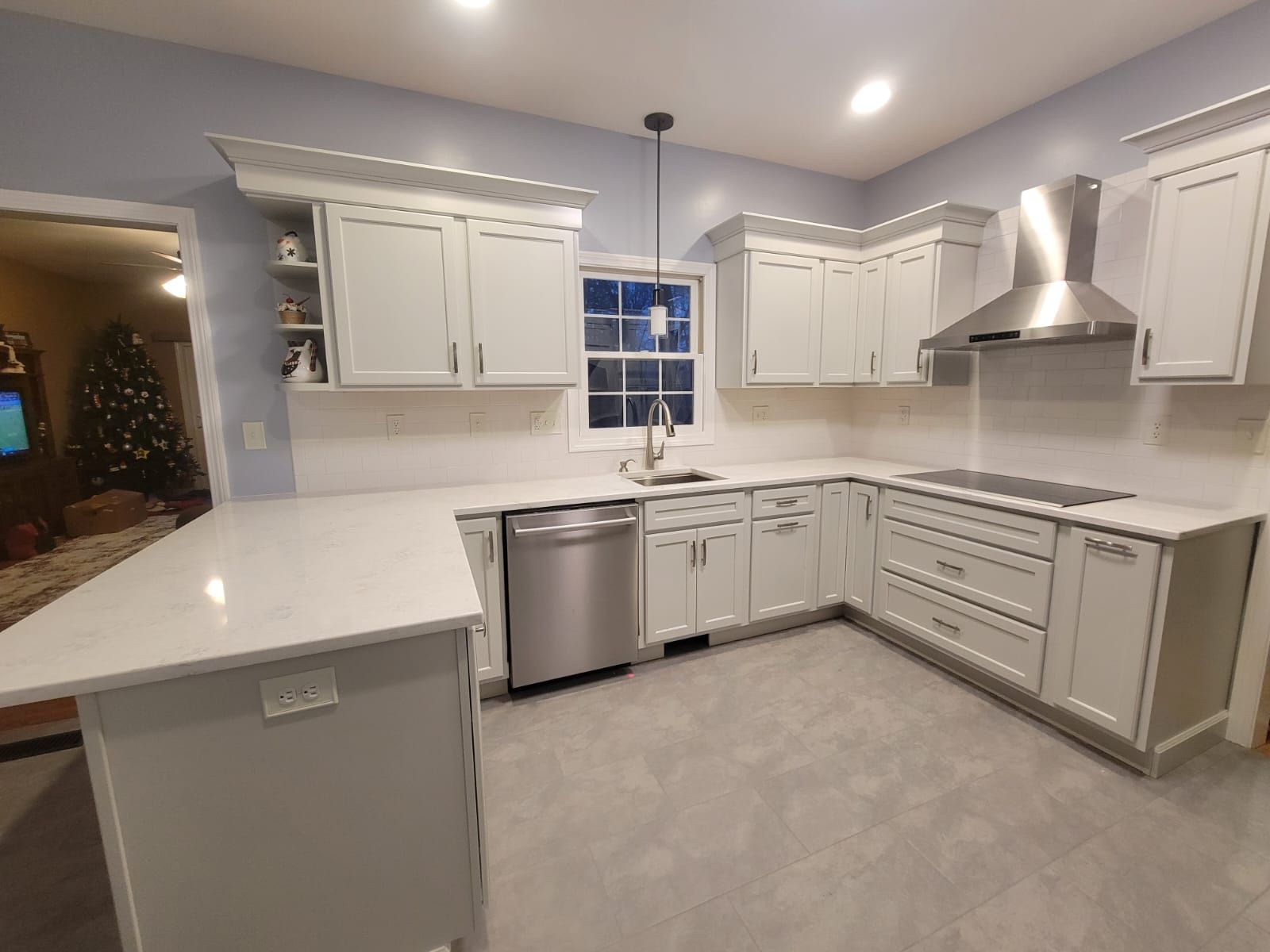 L-shaped kitchen with white cabinets, stainless steel appliances, white countertops, and pale blue walls.