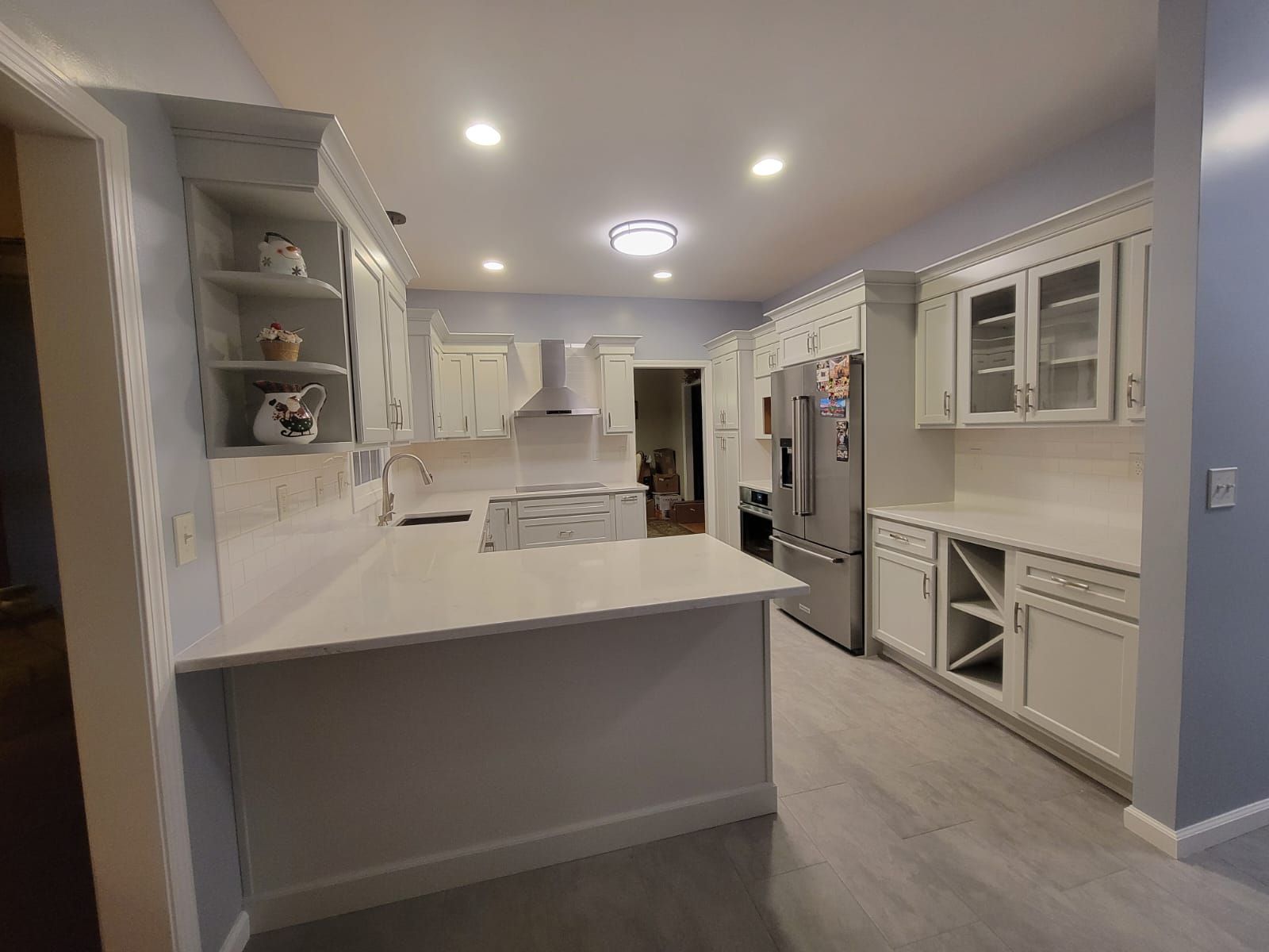 Newly renovated white kitchen with light gray floors, stainless steel appliances, and white countertops.