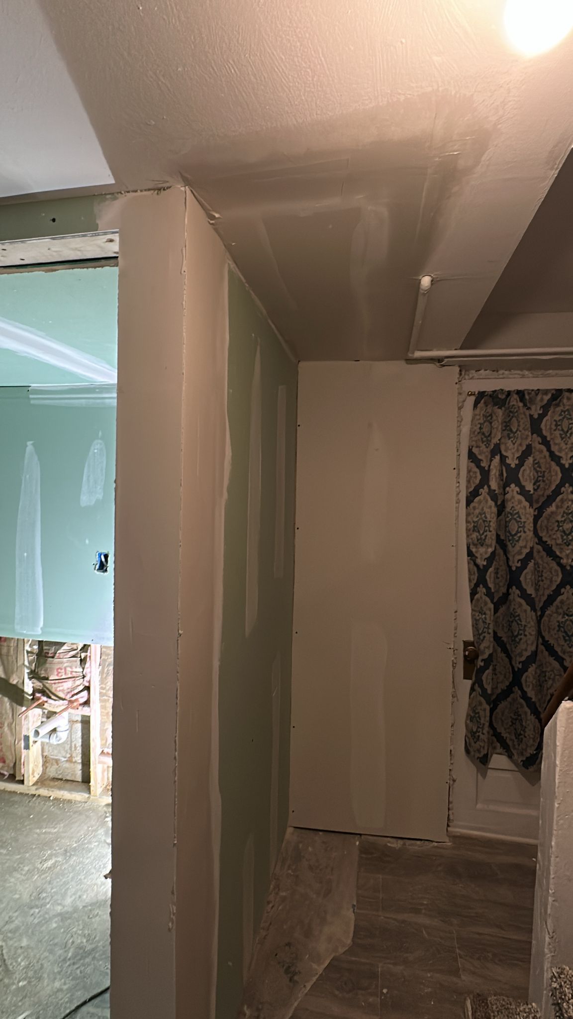 Newly installed drywall in a home; a hallway with unfinished walls and ceiling.