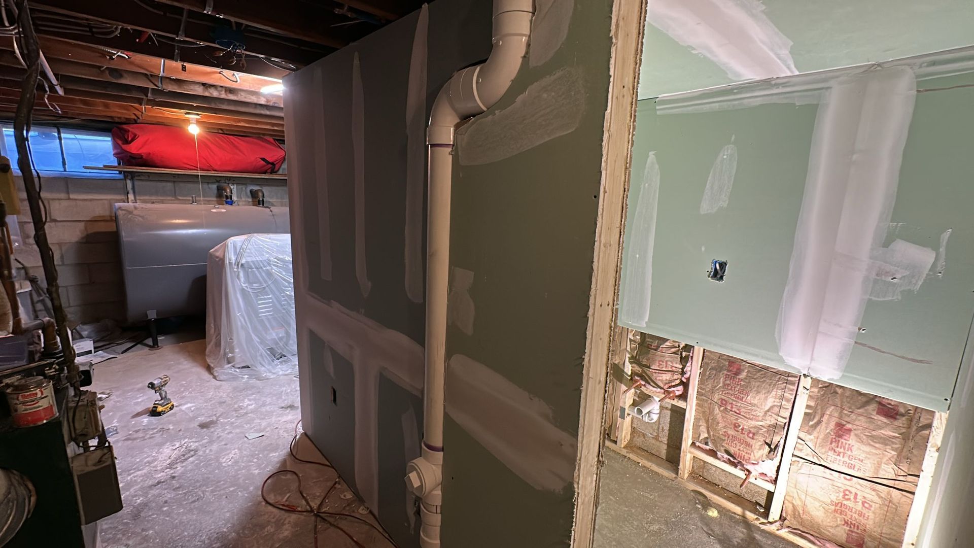 Basement renovation. Drywall installed around plumbing and partially on a wall with exposed insulation.