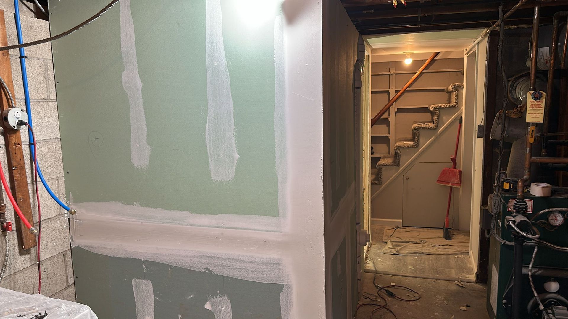 Basement renovation with partially finished walls, a staircase, and tools.